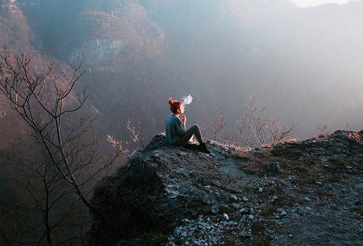 woman sitting on top of mountain while smoking, cannon, smoke