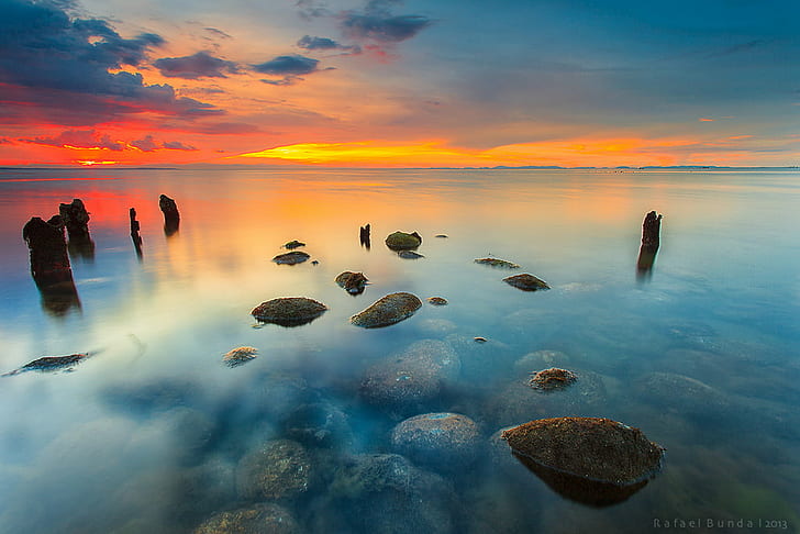landscape photography of body of water with rocks during golden hour