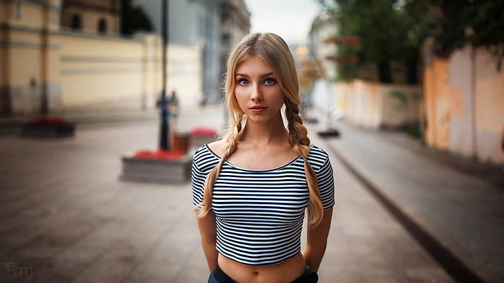 women's white and black striped top, selective focus photography of woman standing on street