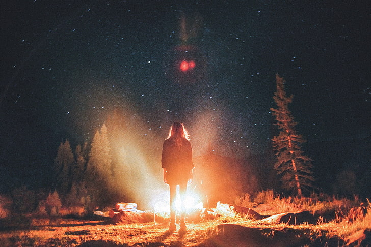 person standing near bonfire surrounded pine trees, women, campfire