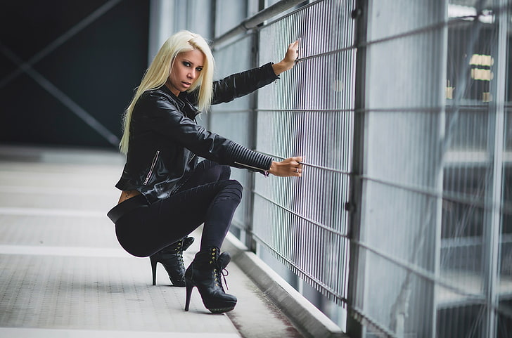 woman wearing black jacket, pants, and and stiletto platform booties sitting near grey metal barrier, HD wallpaper