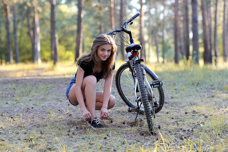 woman in black shirt and blue short shorts sitting beside bicycle, HD wallpaper