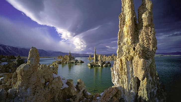 white rock formations near ocean water under cloudy sky during daytime