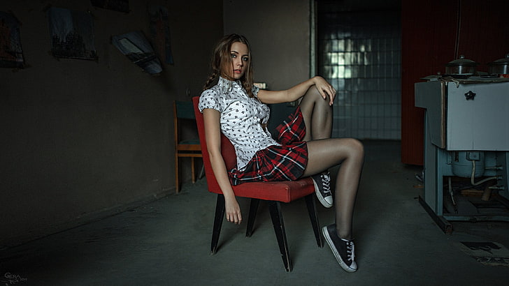 women's red and green plaid miniskirt, woman wears white and black button-up shirt sit on red leather armless chair
