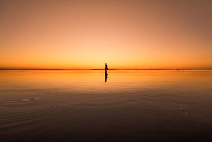 calm body of water, silhouette photo of person standing above body of water