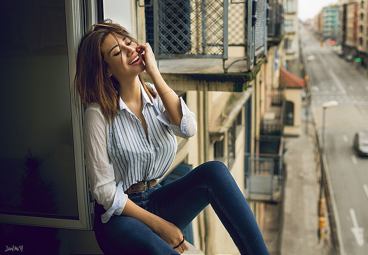 woman in white dress shirt with blue denim jeans sitting on window