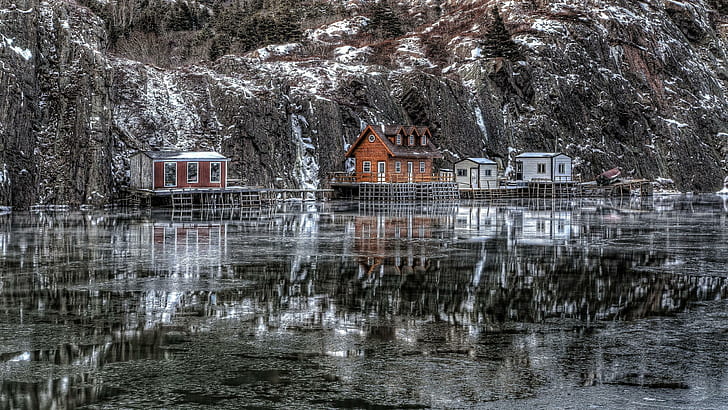 Superb winter scenery, wooden houses near frozen lake and mountains