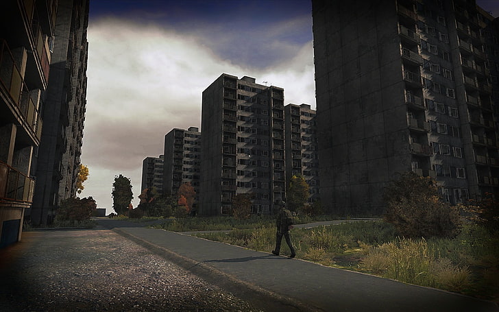 person walking near concrete high-rise buildings, apocalyptic