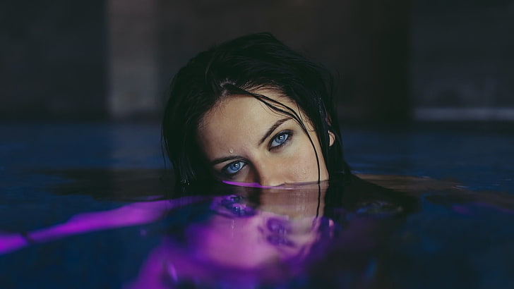 woman's face, woman with blue eyes and black hair submerged in water