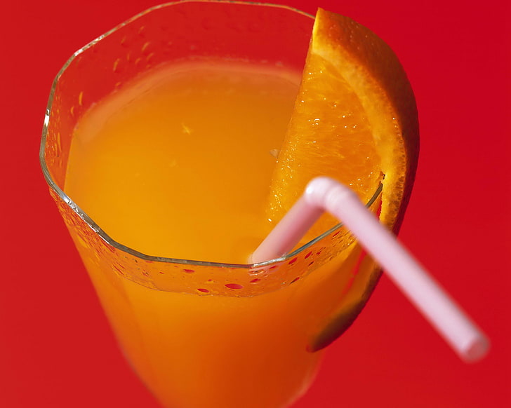 clear drinking glass, orange juice, straw, close-up, red background