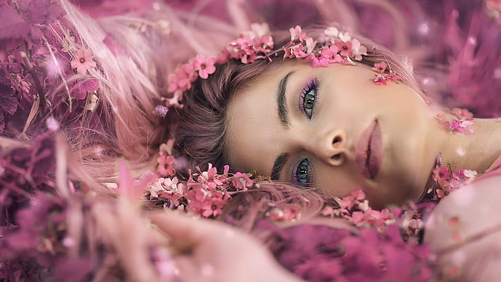 women's pink lipstick and black false eyelashes, closeup photo of woman wearing pink flower headdress lying on ground