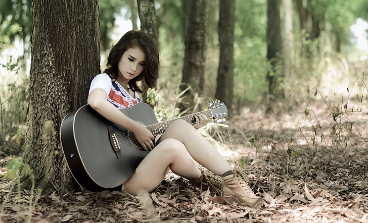 black acoustic guitar, woman in white and red top holding black dreadnought acoustic guitar