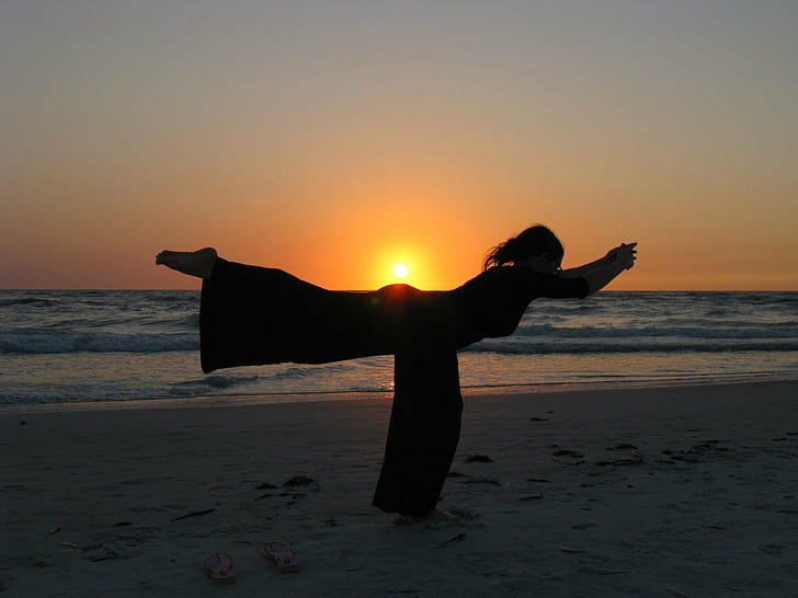 silhouette of woman doing yoga during sunset on beach, longboat key