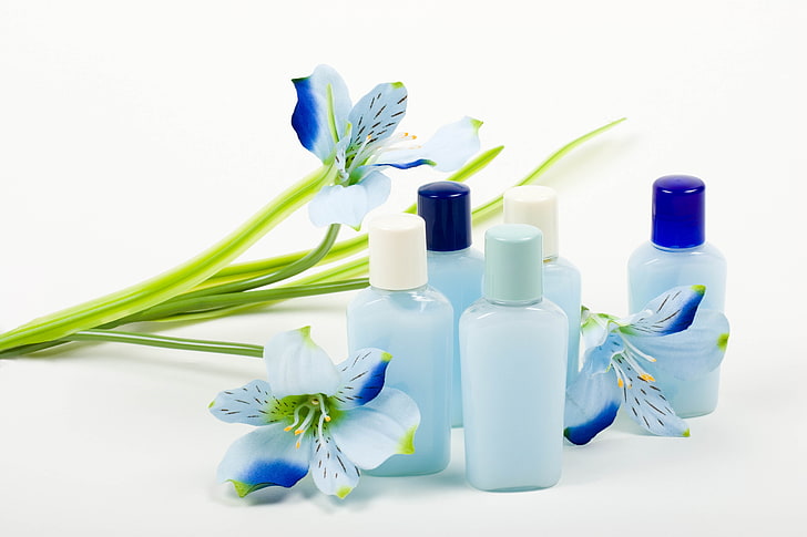 five blue plastic bottles, cosmetics, flowers, white background
