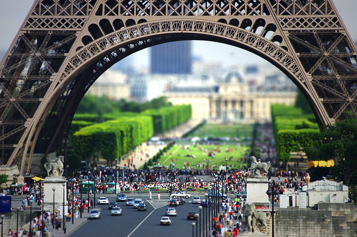 tilt-shift photography of Eiffel Tower and cars, white and black cars near group of people