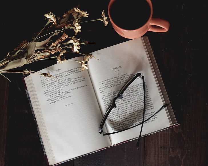 black framed eyeglasses and white and black book, coffee, flowers