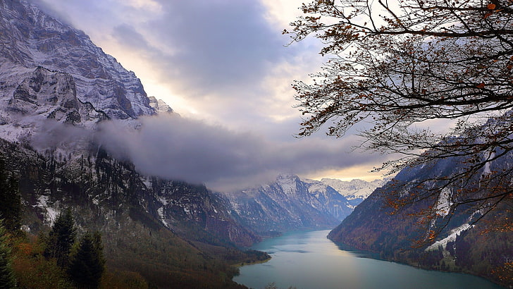 body of water, mountain, and green leaf trees, blue lake between two snow-covered mountains