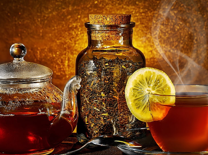 amber glass bottle, tea kettle, steam, cup, lemon, tea leaves