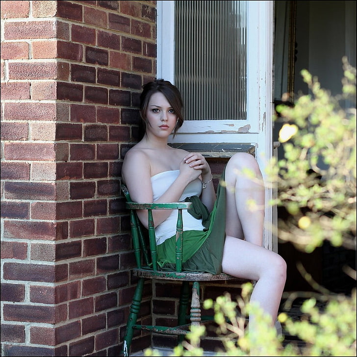 woman sitting on green and brown armchair on corner of house wallpaper