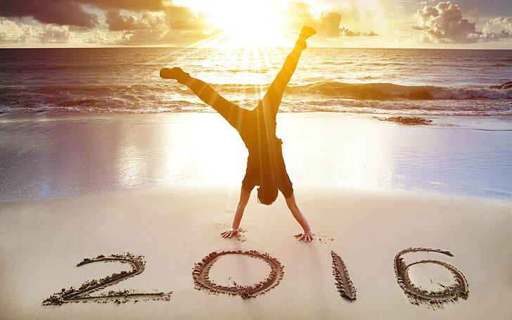 New Year 2016 beach, silhouette photo of man doing cartwheel in seashore with 2016