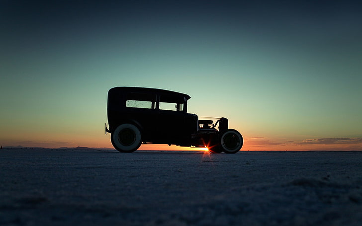 silhouette photography of vintage car on plain field during golden hour