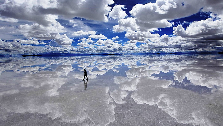 man walking of body of water under cloudy sky during daytime
