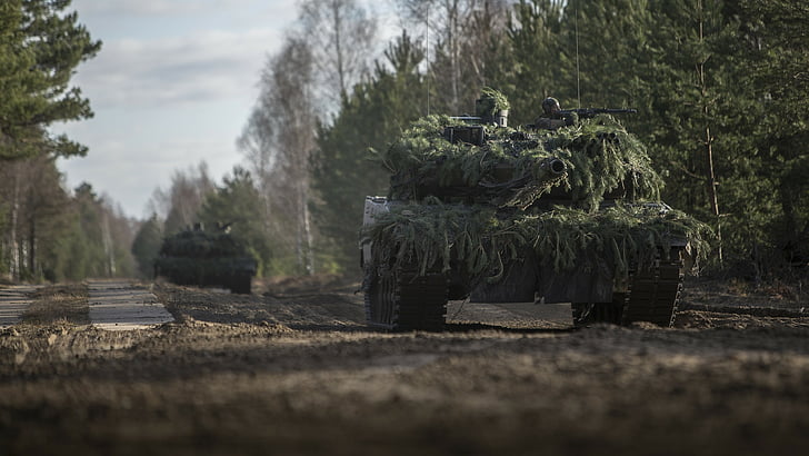 two battle tanks with green leaves camouflage on road, Leopard 2A6