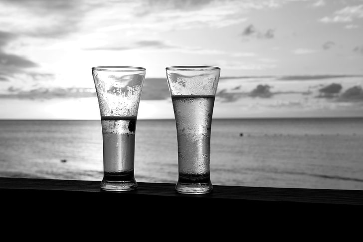two clear glass candle holders, glasses, beach, sky, water, food and drink