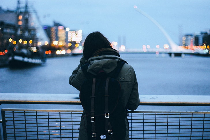 women's black leather coat and black backpack, person wearing gray jacket
