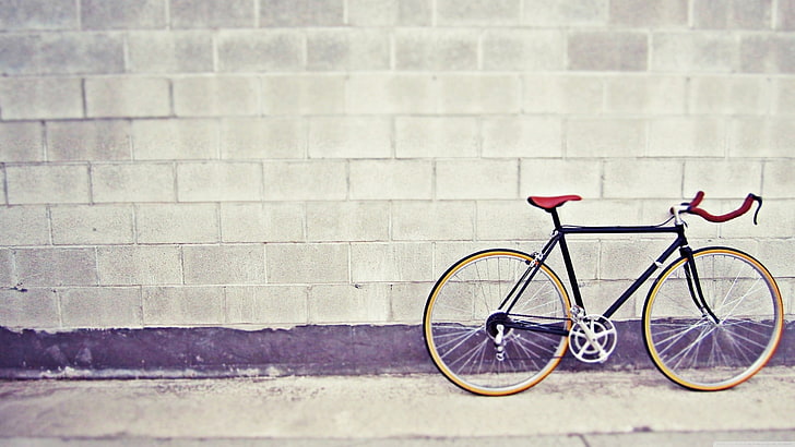 black and brown commuter bike, black road bike parked near gray concrete wall