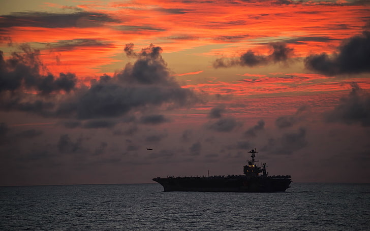 Nimitz-class Aircraft Carrier USS Jo, silhouette of ship on ocean under clouded sky during golden hour
