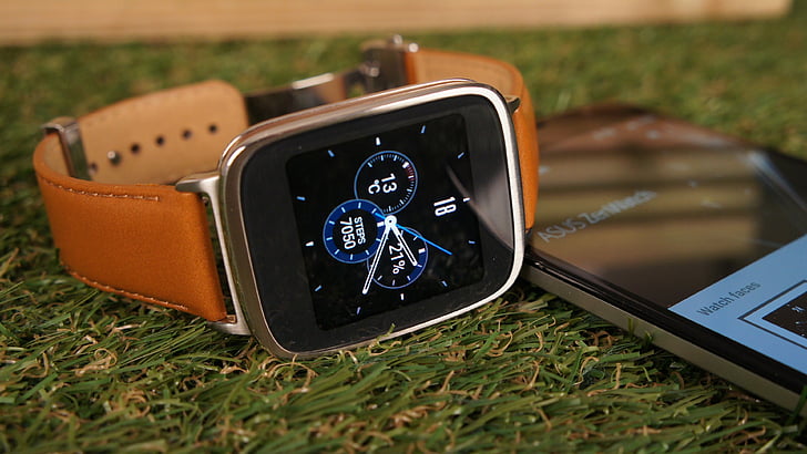 silver aluminum case Apple Watch with brown leather strap on grass