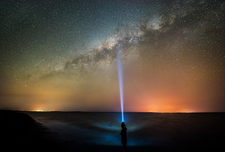 silhouette of boy pointing flashlight ray on Milky Way sky, starry sky illustration