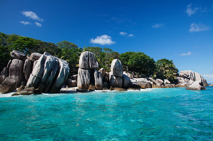 view of gray stones near body of the water surrounded by trees, la digue, seychelles, la digue, seychelles