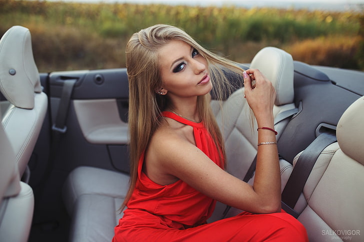 woman wearing red halter dress sitting inside convertible car