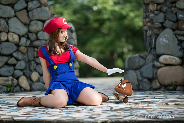 women's Super Mario costume, shallow focus photography of smiling woman in Mario costume sitting on floor