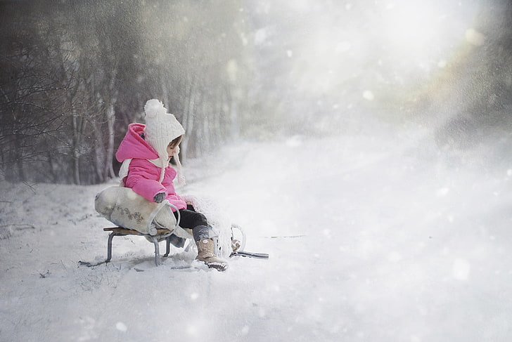 kid in pink bubble hoodie sitting on sled during winter, children