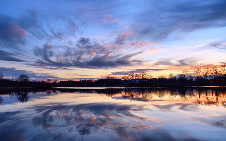 Beautiful sunset, calm lake, reflection in the water, shore trees, sky clouds