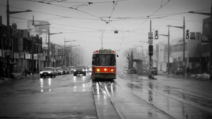 red and black city tram, cityscape, selective coloring, rain