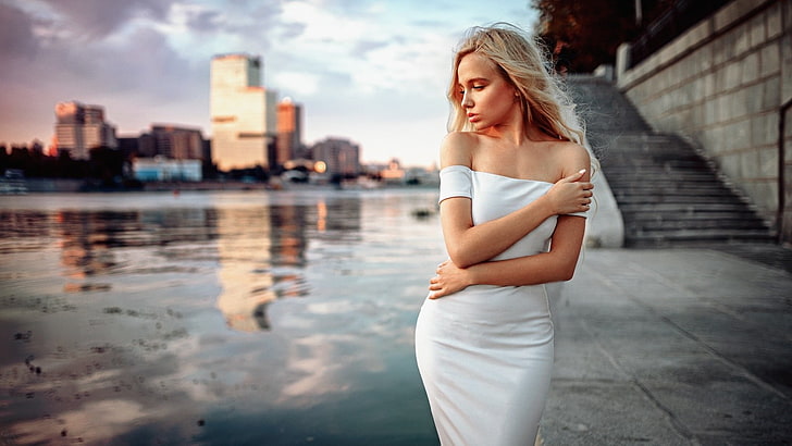 woman wearing white strapless dress standing near building during daytime