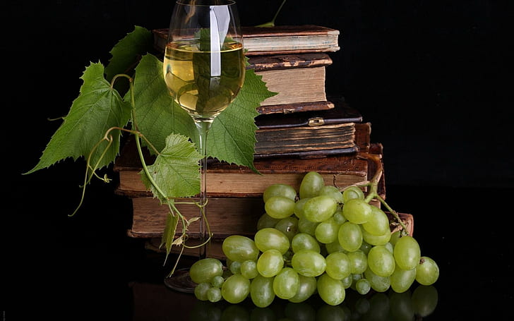 Wine and books, green grapes with clear long stem wine glass