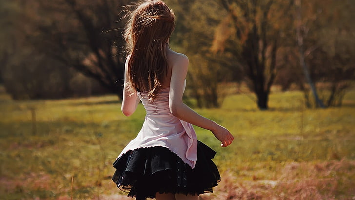 women's black skirt, woman wearing pink and black strapless dress walking in grass field