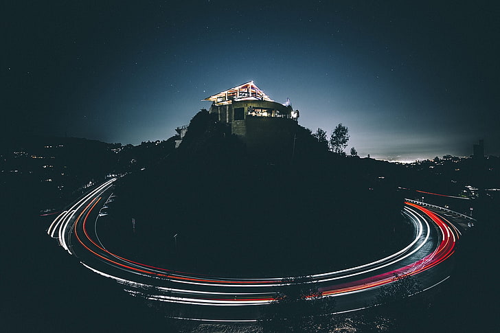 timelapse photography of house on top of hill beside road during nighttime