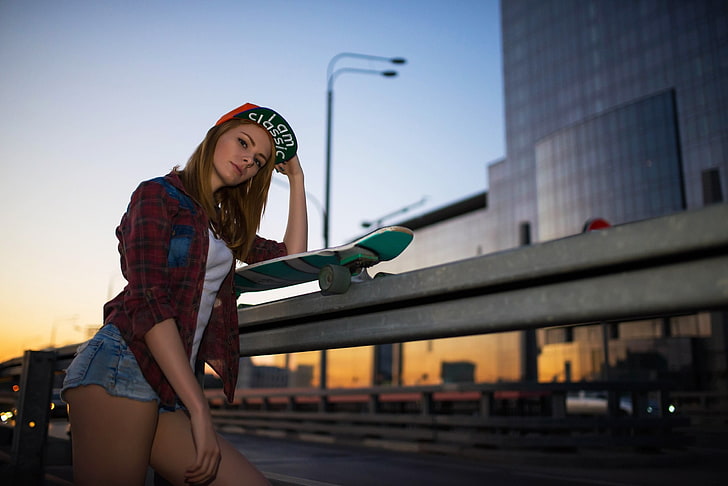 woman wearing red sport shirt and blue short shorts leaning on gray rails with skateboard, HD wallpaper