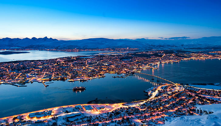 Norway, tromso, night, snow covered city near lake and bridge