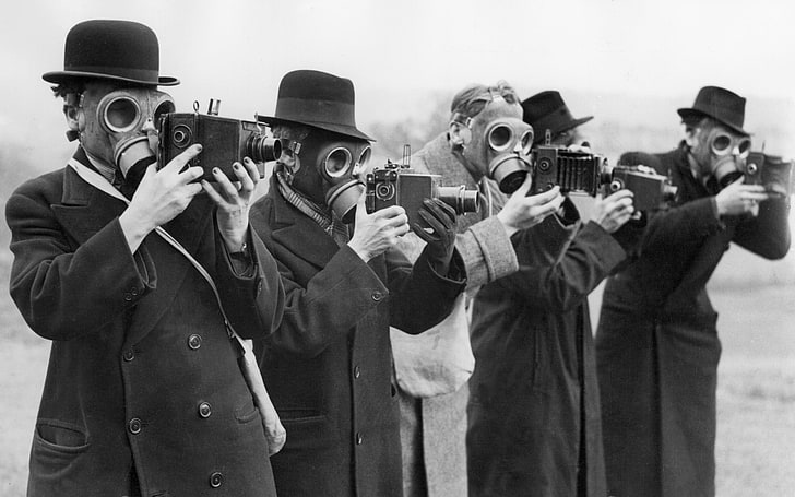 grayscale photo of men wearing gas masks and holding cameras