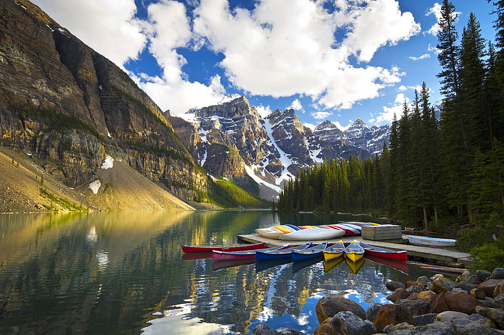 red, blue, and yellow canoe boats, trees, mountains, lake, reflection