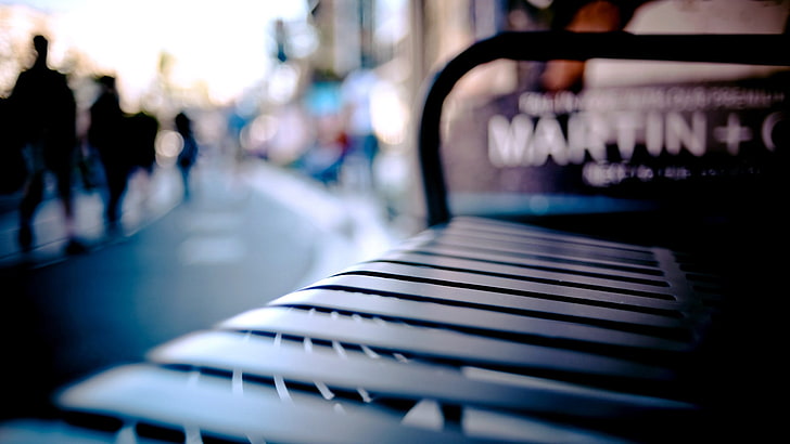 black metal bench, cityscape, blurred, depth of field, seat, focus on foreground