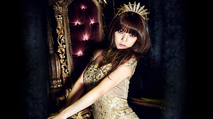 photo of woman wearing brown dress and crown beside chair, AOA