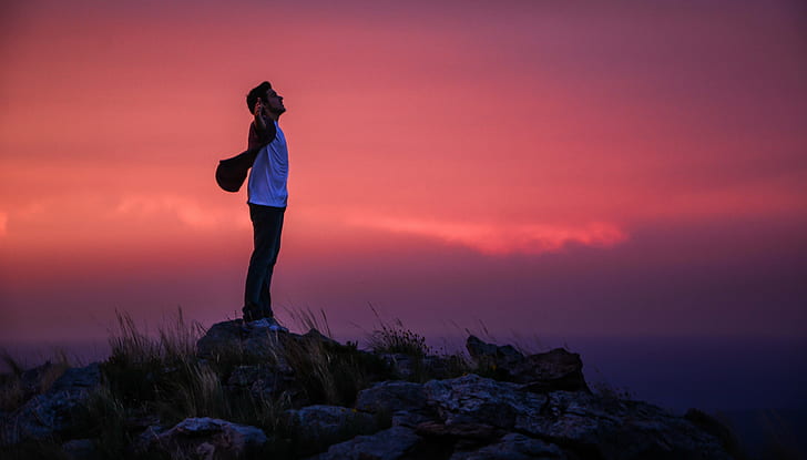 man wearing white crew neck shirt standing on gray rock during dawn